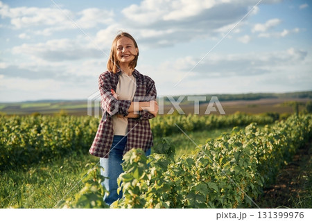 Sunny weather, standing. Young woman is on the beautiful agricultural field at daytime Sunny weather, standing. Young woman is on the beautiful agricultural field at daytime 131399976