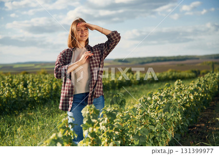Sunny weather, standing. Young woman is on the beautiful agricultural field at daytime Sunny weather, standing. Young woman is on the beautiful agricultural field at daytime 131399977