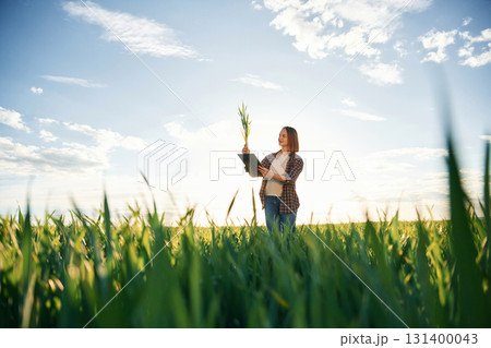 Far view, standing. Young woman is on the beautiful agricultural field at daytime 131400043