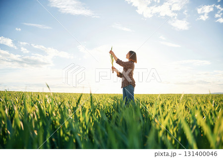 Far view, standing. Young woman is on the beautiful agricultural field at daytime Far view, standing. Young woman is on the beautiful agricultural field at daytime 131400046