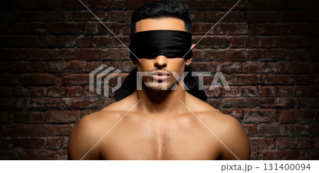 Shirtless man blindfolded posing in front of brick wall 131400094