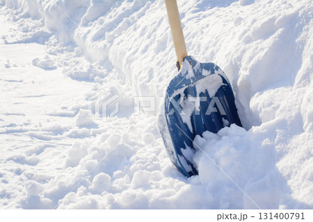 Cleaning snow after a snowstorm in winter. Snow shovel near a big snowdrift before removing snow in a sidewalk Cleaning snow after a snowstorm in winter. Snow shovel near a big snowdrift before removing snow in a sidewalk 131400791