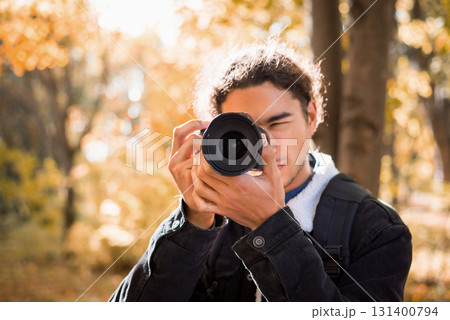 Male photographer with amateur camera taking picture of nature in the park in a sunny autumn day 131400794