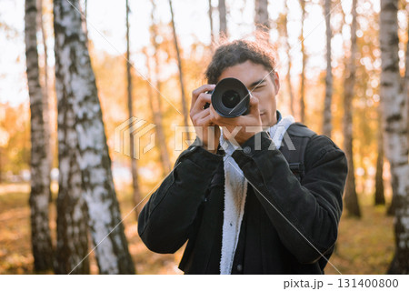 Portrait of a young male photographer shooting landscapes in the autumn forest 131400800