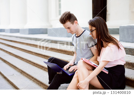 Students sitting on the stairs of old university working on project, communicate, search for information in the Internet 131400810