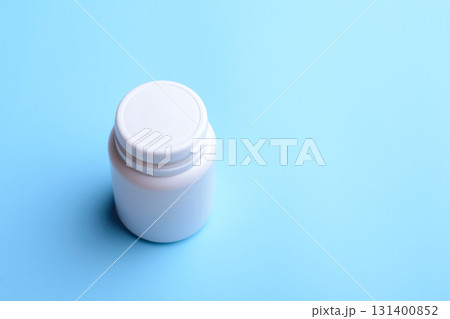 White plastic bottle closed with a cap with pills stands on table. Concept of medicine White plastic bottle closed with a cap with pills stands on table. Concept of medicine 131400852