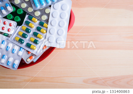 Red bag with many different pills against wooden table with place for inscription. Concept of pills, health care, medicine Red bag with many different pills against wooden table with place for inscription. Concept of pills, health care, medicine 131400863