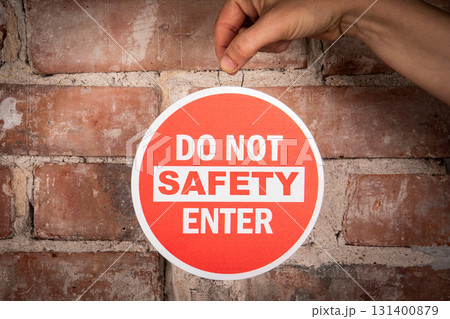 Safety Warning Sign on Brick Wall with Hand Holding Do Not Enter Label 131400879
