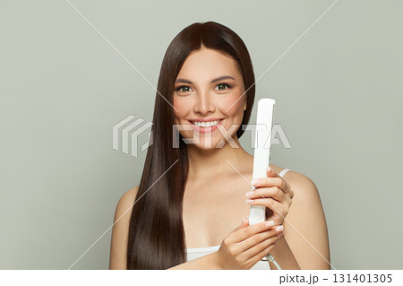 Excited woman brunette with long straight smooth hairstyle using hair straightener iron  131401305