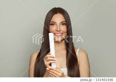 Charming woman brunette with long straight smooth hairstyle using hair straightener iron 131401306