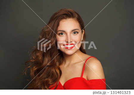 Smiling woman with long hair and make-up on black background. Gorgeous woman with curly hairstyle 131401323