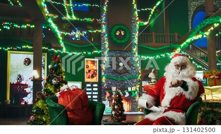 Man dressed as Santa Claus being late to children charity event after falling asleep on chair. Elderly person rushing to visit kids after dozing off and falling behind schedule, camera A Man dressed as Santa Claus being late to children charity event after falling asleep on chair. Elderly person rushing to visit kids after dozing off and falling behind schedule, camera A 131402500