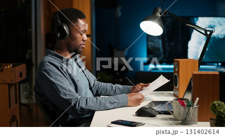 Investor contacting his accountant at home desk to go over current budget balance, boosting earnings via foreign investments. Man reviewing financial assets with consultant. Camera B. 131402614