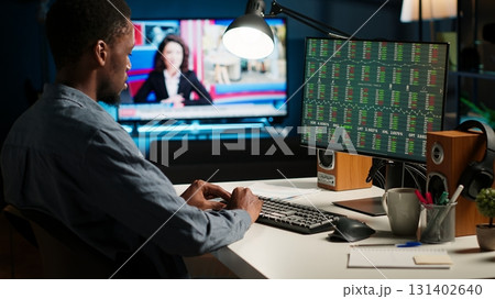 Financial advisor examines cryptocurrency trade market from his loft workstation, looks at online global exchange statistics on desktop. Guy studying stock analysis to secure capital funds. Camera B. Financial advisor examines cryptocurrency trade market from his loft workstation, looks at online global exchange statistics on desktop. Guy studying stock analysis to secure capital funds. Camera B. 131402640