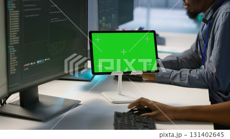 Team of programmer using green screen tablet, working in server farm to optimize it for data processing requirements. Teamworking colleagues coding on chroma key device in data center, camera A 131402645