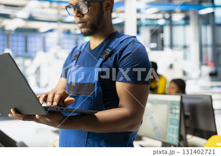 Black engineer testing solar technology in renewable energy facility on pc, focusing on software troubleshooting and performance metrics. Eco friendly industrial operations on laptop. 131402721