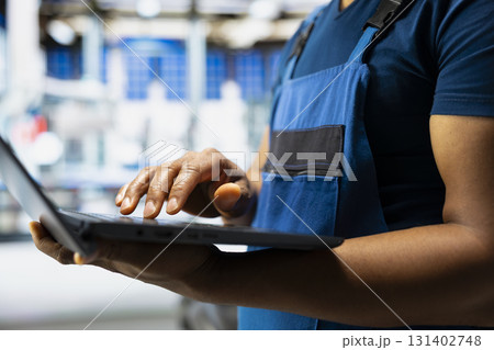 Male engineer works on solar energy software settings in high tech factory, optimizing the production process. Optimal system configuration with digital tools and industrial robotics. Close up. 131402748