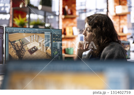 Architectural professional uses CAD software to create a floor plan layout, user interface supports 3D modeling and rendering. Woman developer visualize the final design with detailed home interior. 131402759