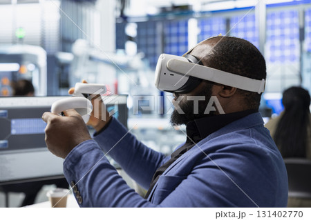 Photovoltaics factory engineer designing on CAD software with VR headset, working in solar panels manufacturing plant. Black technician inspecting assembly lines in virtual reality. 131402770