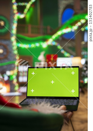 Person dressed as Santa Claus using chroma key laptop to read letters from kids. Man portraying Father Christmas answering emails received from children using isolated screen notebook 131402783