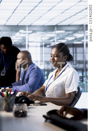 African american technician in data center while running system diagnostic tests and error checking utilities. Woman next to colleagues looking for network issues affecting server performance 131402805