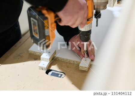 Close-Up of Worker Drilling Wooden Boards to Prepare for Further Processing 131404112