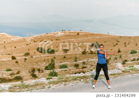 Determined Female Athlete Stretching After an Intense Run Through Rugged Mountain Terrain. 131404299
