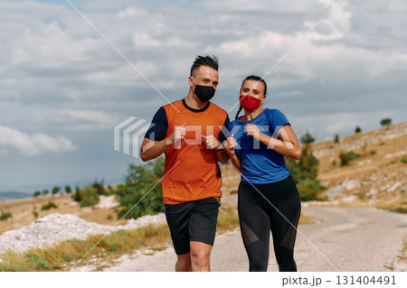Couple running in nature at morning wearing protective face masks Couple running in nature at morning wearing protective face masks 131404491