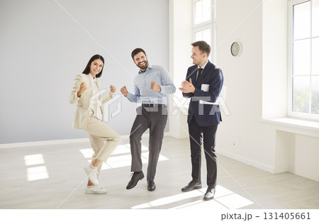 Cheerful family couple in bright empty room with realtor smiling and celebrating new house purchase. Cheerful family couple in bright empty room with realtor smiling and celebrating new house purchase. 131405661