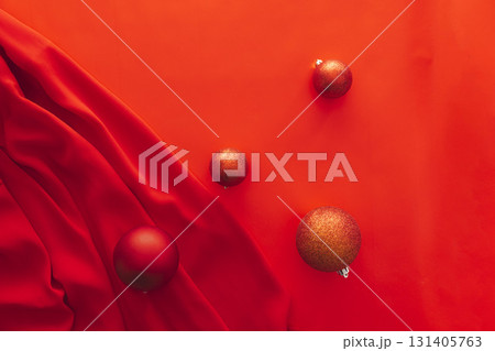 Christmas balls on red fabric background with elegant folds and copy space minimal festive decoration with shiny ornaments concept of holiday celebration winter marketing seasonal design advertising 131405763