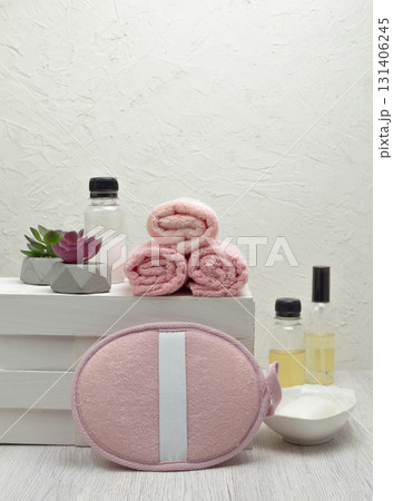 Rolls of clean pink towels and a houseplant on a white table with shampoo, conditioner, and soap, offering copy space. Rolls of clean pink towels and a houseplant on a white table with shampoo, conditioner, and soap, offering copy space. 131406245