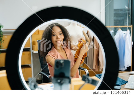 Young influencer showcasing clothing in a creative workspace, highlighting ecommerce, digital marketing 131406314