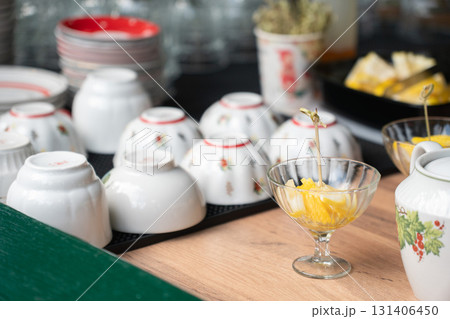 Traditional porcelain bowls with floral patterns displayed on a table alongside glass cups of fresh fruit 131406450