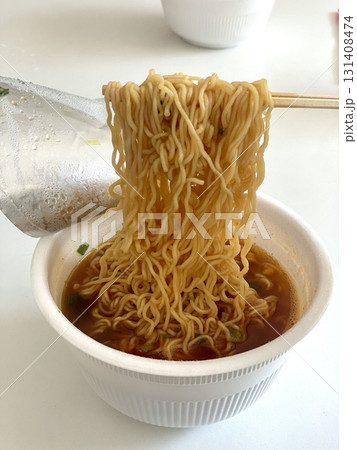 A steaming cup of ramyeon, featuring flavorful noodles and rich broth. Perfect for quick meals or snack-related projects, capturing the essence of comfort food in a convenient, portable format. A steaming cup of ramyeon, featuring flavorful noodles and rich broth. Perfect for quick meals or snack-related projects, capturing the essence of comfort food in a convenient, portable format. 131408474
