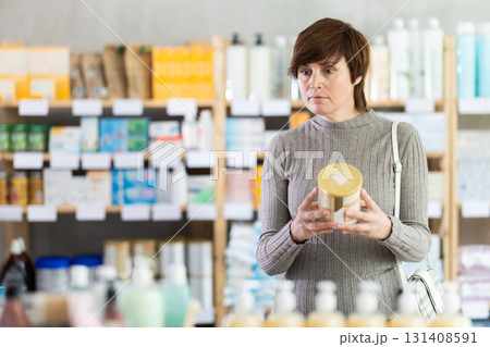 Thoughtful woman choosing baby formula in pharmacy 131408591