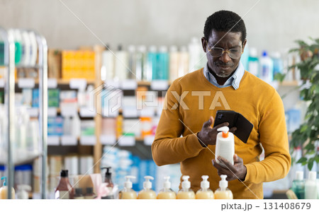 Male customer using smartphone to choose skincare product in pharmacy 131408679