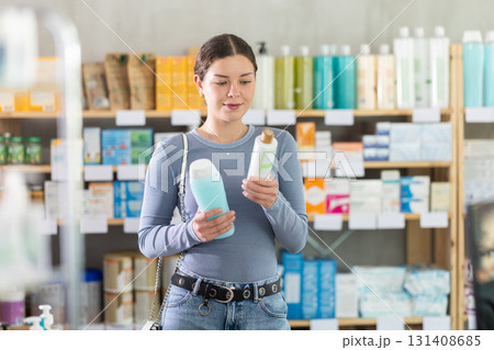 Young girl choosing shampoo in drugstore Young girl choosing shampoo in drugstore 131408685