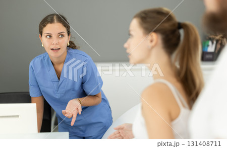 Woman stands near the reception of the dentistry and communicates with the administrator 131408711