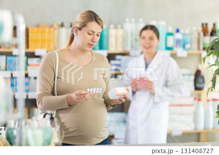 Pregnant woman choosing pills with help of pharmacist 131408727