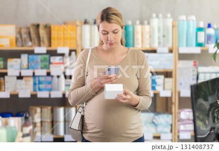 Pregnant woman scanning qr code of pills 131408737