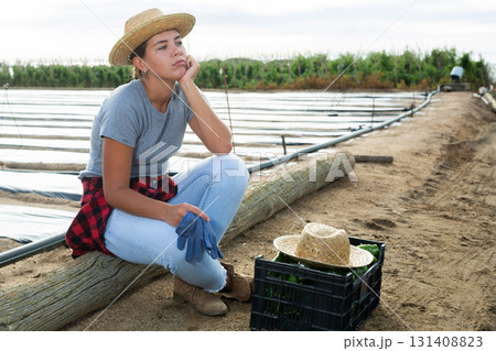 Thoughtful girl farmer on vegetable field Thoughtful girl farmer on vegetable field 131408823