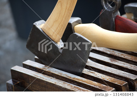 Close of axes with wooden handles resting on a wooden surface, ready for use. Close of axes with wooden handles resting on a wooden surface, ready for use. 131408843