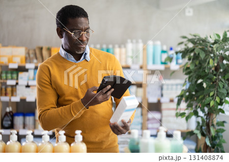 African man in pharmacy scans QR code on cream African man in pharmacy scans QR code on cream 131408874