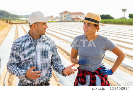 Man and girl farmers talking friendly in field during break in work Man and girl farmers talking friendly in field during break in work 131408954