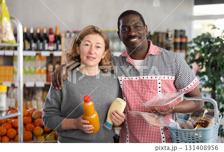 African husband and his wife are shopping in grocery store, looking for something in shop window African husband and his wife are shopping in grocery store, looking for something in shop window 131408956