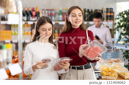 Woman and her teenage daughter choosing hamburger or beef entrecote in grocery Woman and her teenage daughter choosing hamburger or beef entrecote in grocery 131409062