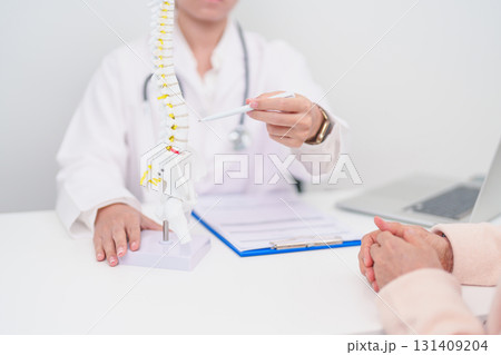 Elderly Patient consulting Doctor with Spine anatomy for Spinal Cord Disorder and disease, Back pain, Lumbar, Sacral pelvis, Cervical neck, Thoracic, Coccyx, Orthopedist, chiropractic, Office Syndrome 131409204