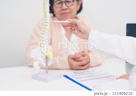 Elderly Patient consulting Doctor with Spine anatomy for Spinal Cord Disorder and disease, Back pain, Lumbar, Sacral pelvis, Cervical neck, Thoracic, Coccyx, Orthopedist, chiropractic, Office Syndrome 131409210