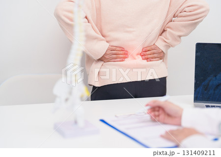 Elderly Patient consulting Doctor with Spine anatomy for Spinal Cord Disorder and disease, Back pain, Lumbar, Sacral pelvis, Cervical neck, Thoracic, Coccyx, Orthopedist, chiropractic, Office Syndrome 131409211