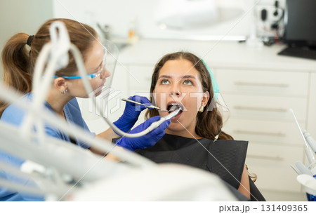 Woman dentist drilling and treating teeth of woman in clinic 131409365